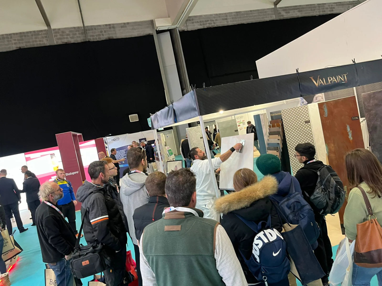 Visitors looking closely at a decorative-finish demonstration at the ISF stand, Coventry 2024.